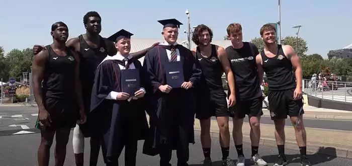 graduating students with Trailfinders Academy players posing for photo