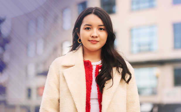 student in white coat standing in front of a building