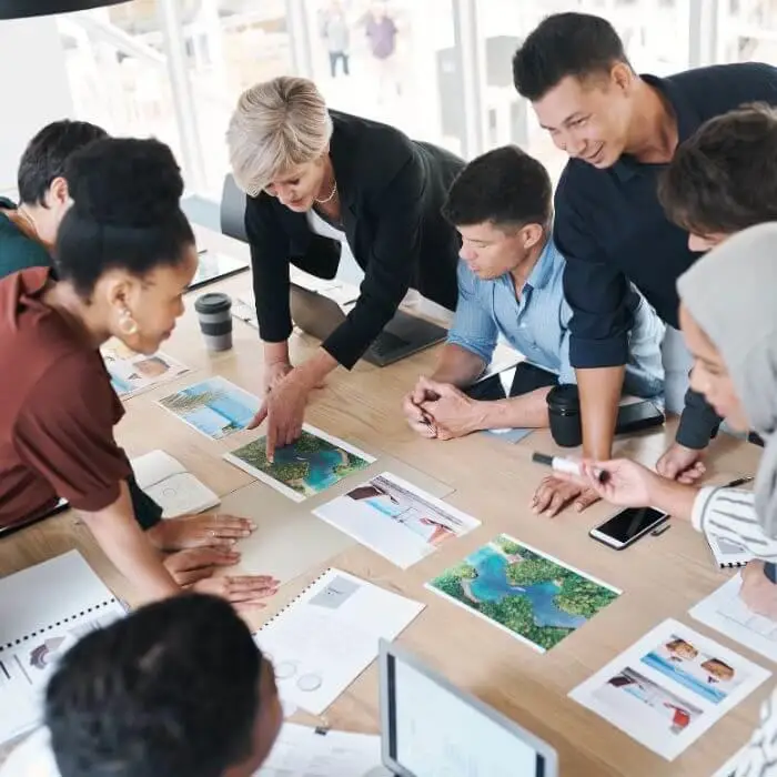 Group of people collaborating over maps and documents on a table.