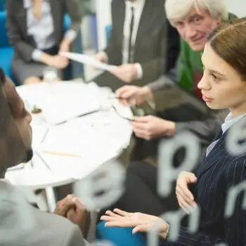 Group of professionals in a meeting, discussing over documents on a table.