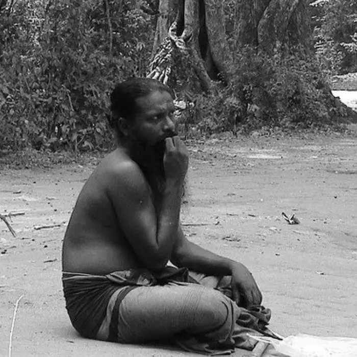 Indigenous person sitting on the ground.