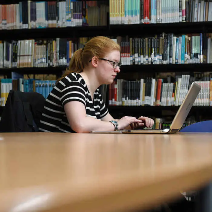 Brunel student sitting at laptop in the library