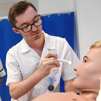 Student shining the torch light into the eye of the patient